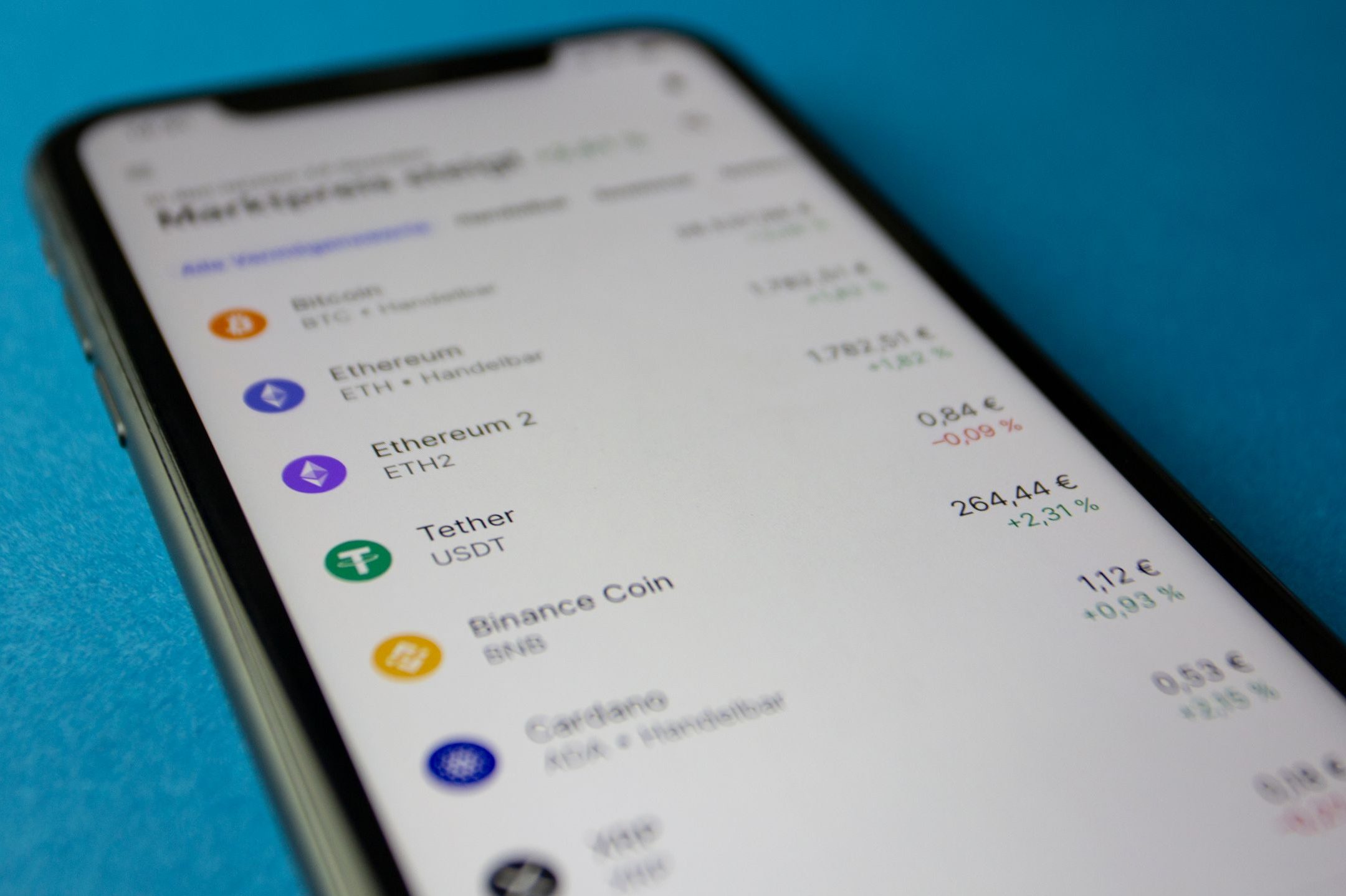 Close-up photo of a smartphone displaying cryptocurrency market data with price listings.
